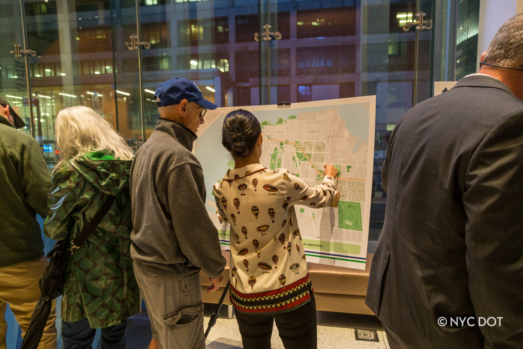 A city planner points at a map next to a member of the public at a public workshop.