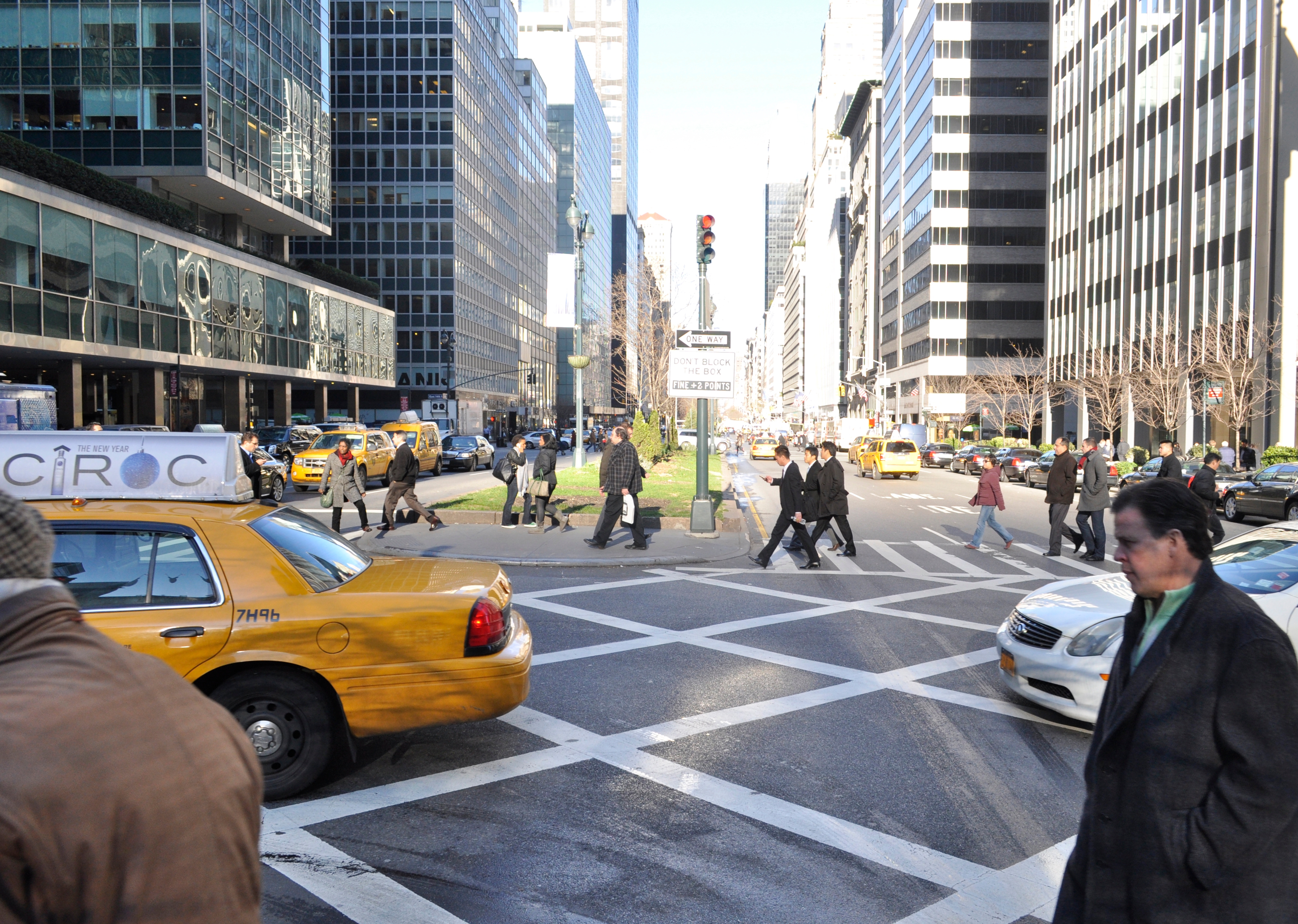 Pedestrians walk to the Park Avenue Medians, a cab drives through the intersection