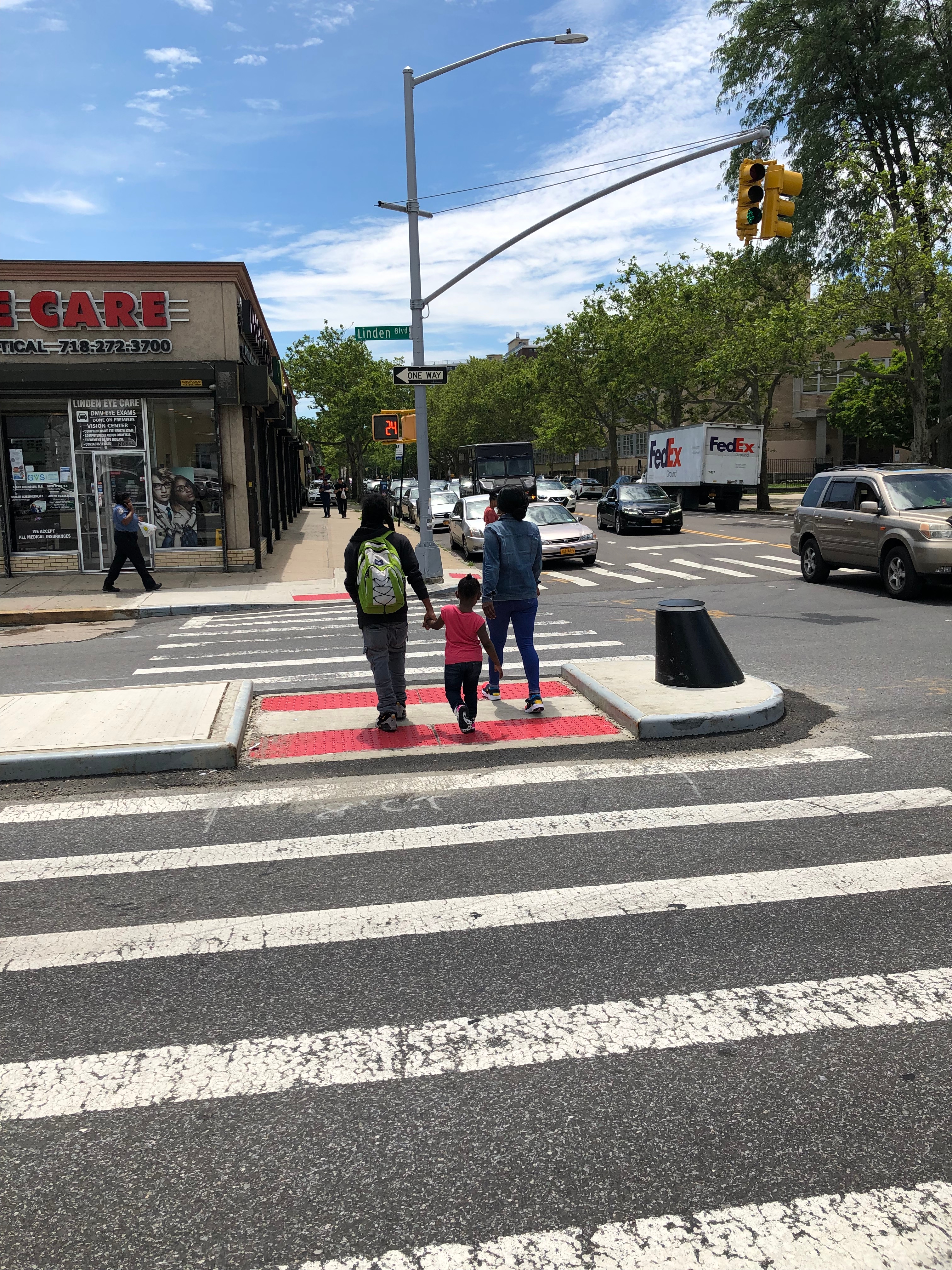 Three pedestrians, including a female child pedestrian, crossing Linden Blvd at Van Siclen Ave, through a newly constructed median tip 