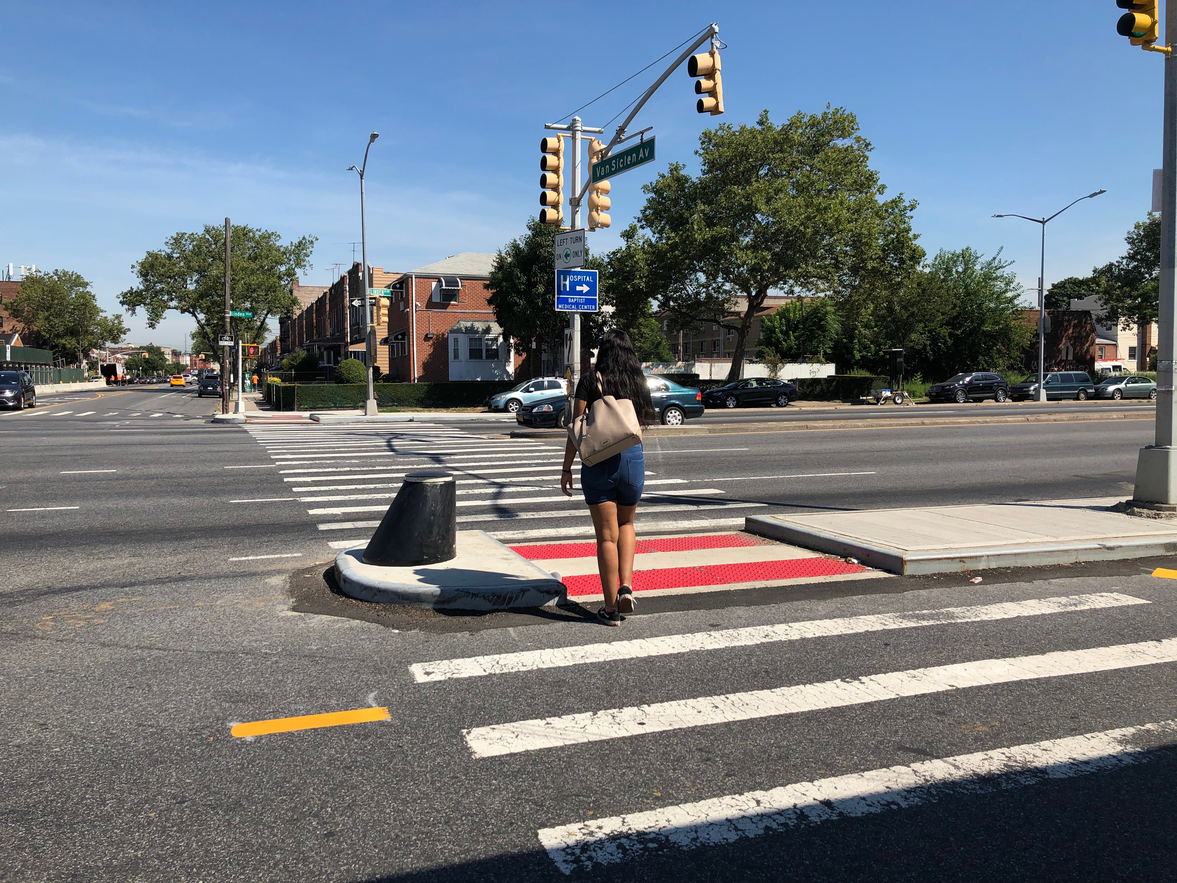 A pedestrian crossing Linden Blvd at Van Siclen Ave, through a newly constructed median tip 