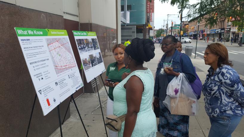 A Street Ambassador talks about transportation safety with folks passing by Restoration Plaza.
