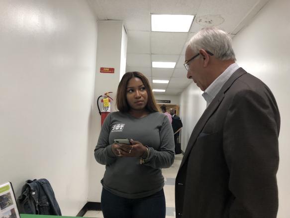 An Ambassador conducts a survey with a participant  attending CB 3's monthly board meeting. 