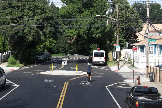 Person cycling on a calm residential street with a traffic circle