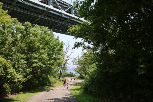 People walking through a park with a bridge above