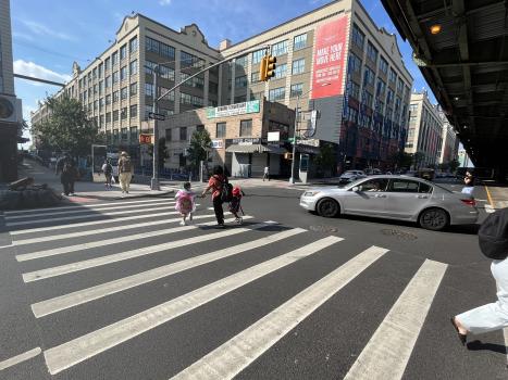Pedestrians walk in the crosswalk across 3rd Avenue