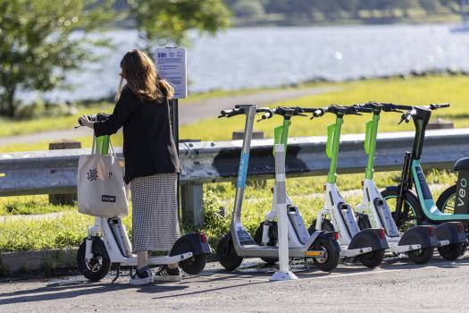 Woman getting ready to ride a shared e-scooter parked in a corral.