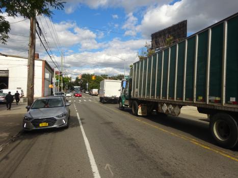 A photo of a street with Red Hook. In the foreground, a large tractor trailer can be seen. 