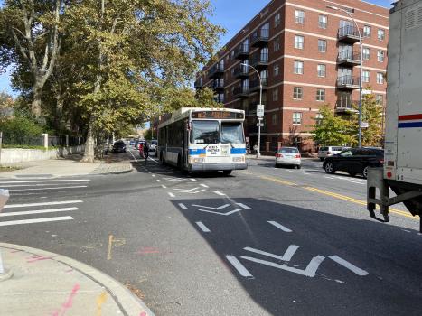 Cyclist riding in bike lane along side MTA bus in traffic lane. 