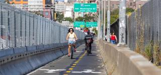 Two cyclists ride on new Washington Bridge protected bike lane.