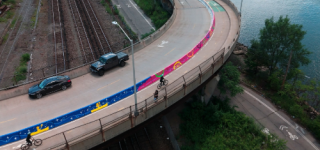 Depot Place in the Bronx shown from an aerial angle, with a colorful mural along a two-way bike lane along the Harlem River