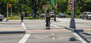 Cyclist and pedestrian cross newly-reconstructed intersection along Pelham Parkway.